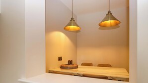 Quarto com cama, duas luzes pendentes, uma mesa de cabeceira e uma tomada na parede.