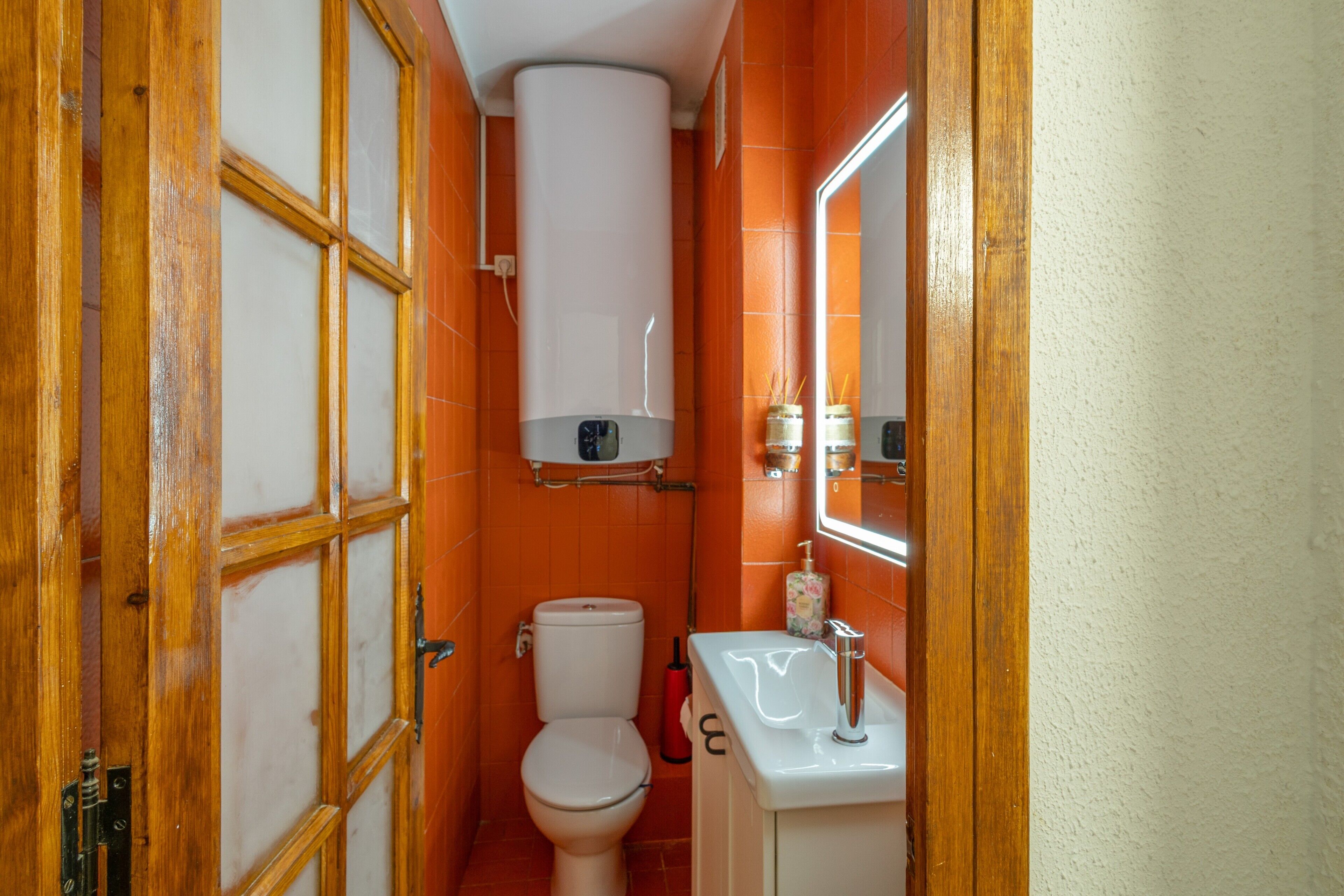 A bathroom with a toilet, a sink, a mirror, and a window.