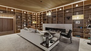 Ein modernes Wohnzimmer mit Kamin, einer Couch, einem Couchtisch und einer Bücherwand voller dekorativer Gegenstände.