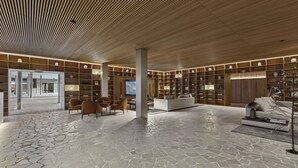 Eine großzügige Lobby mit modernem Design, ausgestattet mit Steinboden, Holzwandverkleidung und einem großzügigen Sitzbereich mit Sofas und Sesseln.