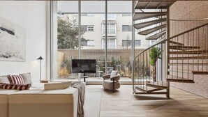Ein modernes Wohnzimmer mit einer Couch, Fernseher und einer Treppe.