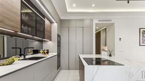 A modern kitchen with a marble countertop, stainless steel appliances, and a built-in oven. - Stylish 3BR Apartment in Madrid (Madrid)