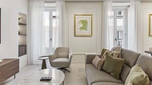 A living room with a sofa, armchair, coffee table, and a framed artwork on the wall. - Stylish 3BR Apartment in Madrid (Madrid)