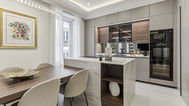 A modern kitchen with a marble countertop, stainless steel appliances, and a dining area with a wooden table and chairs. - Stylish 3BR Apartment in Madrid (Madrid)