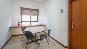 A room with a round table, four chairs, a window with a blind, a wooden door, and a small sign on the wall. - Apt in Condo w/ Pool 300m From the Beach Hor0285 (Salvador)