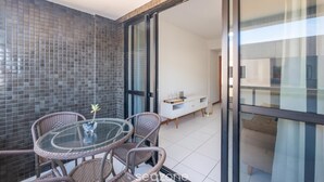 A balcony with wicker chairs, a glass table, and a white cabinet. - Apt in Condo w/ Pool 300m From the Beach Hor0285 (Salvador)