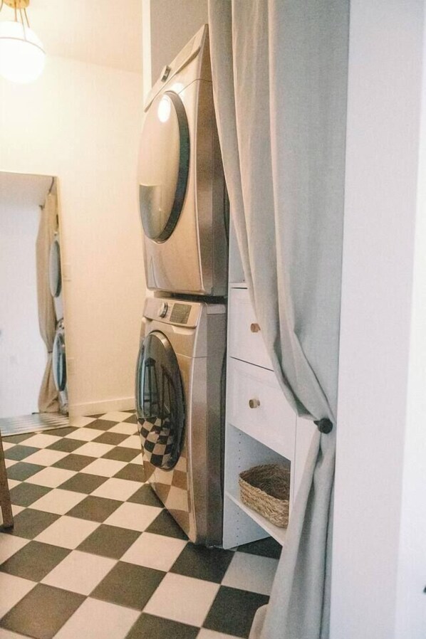 A laundry area with stacked washing machines and a checkered floor.