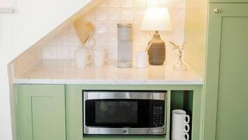 Uma cozinha com micro-ondas, cafeteira e uma luminária sobre o balcão.