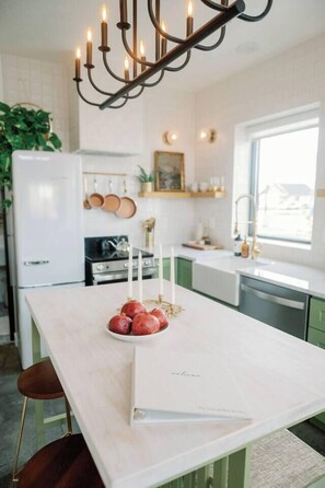 A kitchen with a central island, white cabinets, a stove, and a window.