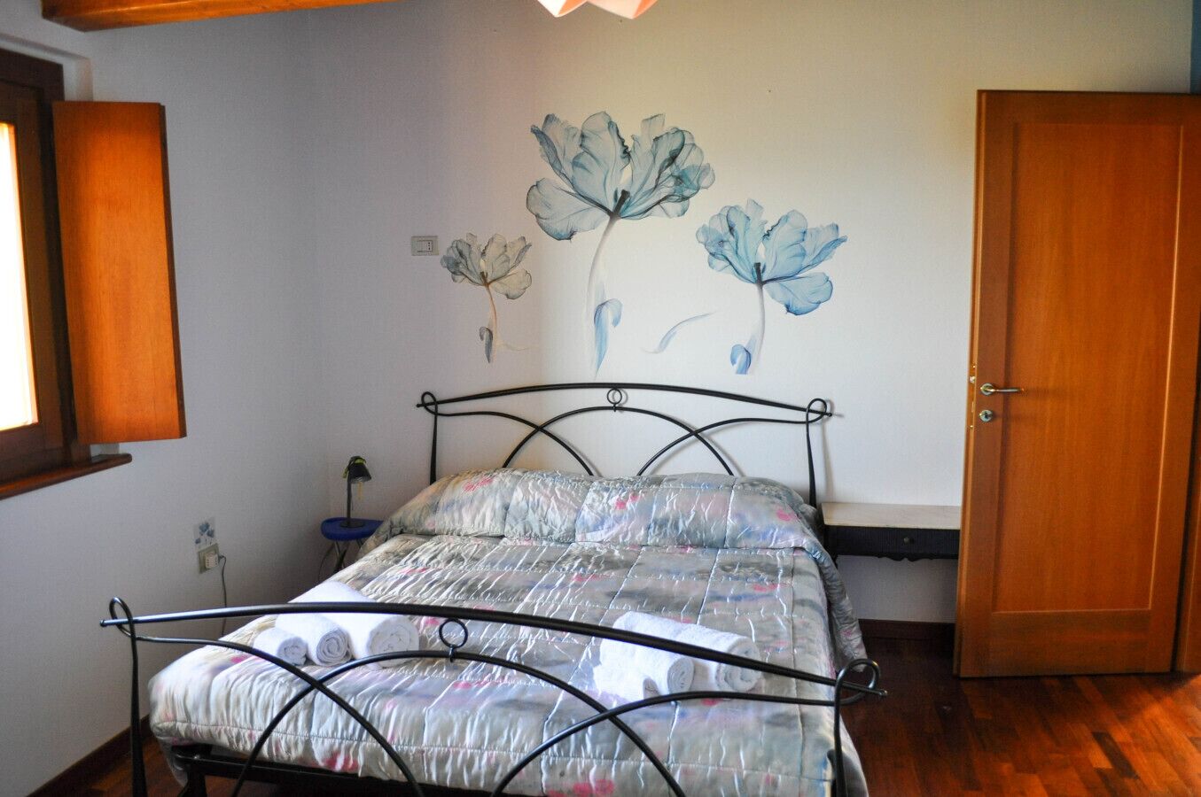 Ein Schlafzimmer mit einem Metallbett, einer Wandablage und einer Tür.