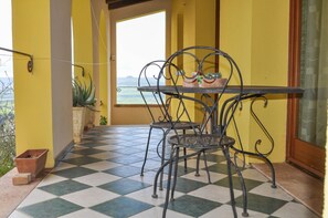A balcony with a checkered floor, yellow walls, and a table with chairs.