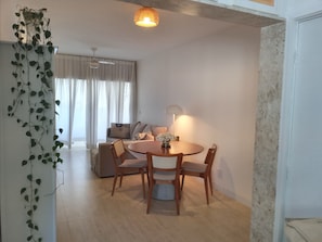 A dining area with a round table, four chairs, a lamp, and a sofa in the background.