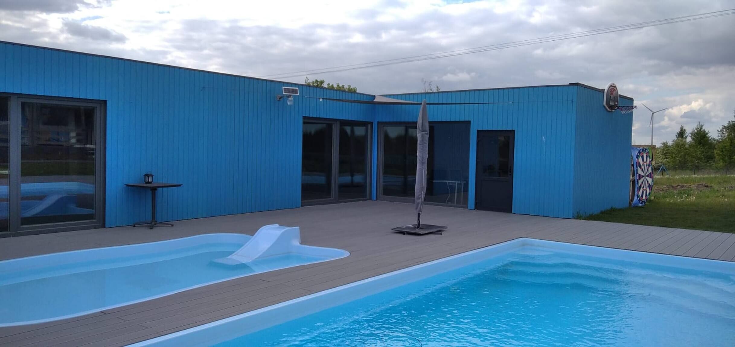 A modern building with a swimming pool, large windows, and a door.