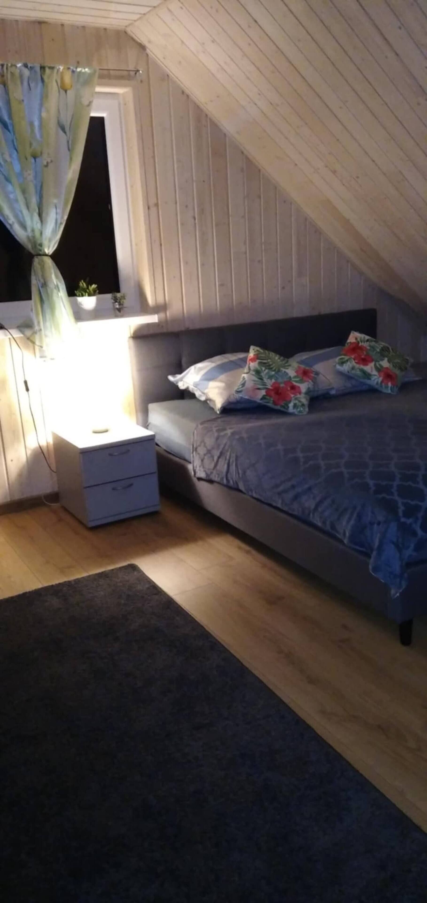 A bedroom with a bed, nightstand, dresser, and a window with curtains.