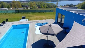 A swimming pool with a deck, lounge chairs, and a covered seating area. - Domek nr 1 "błękitne Wzgórze" (gmina Brzuze)
