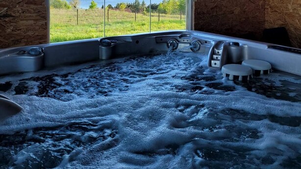 A hot tub with a view of a lake and a wooden interior. - Domek nr 1 "błękitne Wzgórze" (gmina Brzuze)