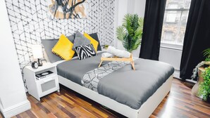 A modern bedroom with a bed, bedside table, lamp, and a view of the outside. - Stylish 2BR Apartment on Brick Lane – Near Shoreditch (London)