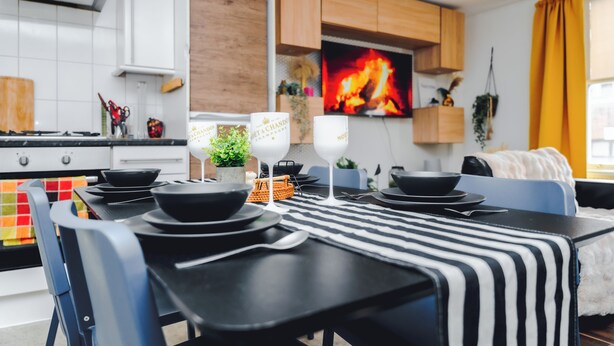 A modern kitchen with a dining area, a TV, and wooden cabinets. - Stylish 2BR Apartment on Brick Lane – Near Shoreditch (London)