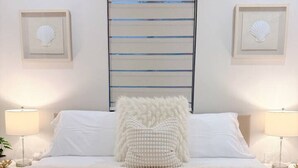 Ein Bett mit weißer Bettwäsche, einem flauschigen Kopfkissen und zwei Nachttischlampen.