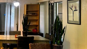 A dining area with a table, chairs, pendant lights, a potted plant, a framed picture, and a bookshelf. - A comfortable, restful stay designed for doctors and Medical Professionals (Houston)