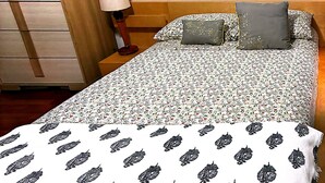 A bed with a floral bedspread and a white blanket with a black pattern. - A comfortable, restful stay designed for doctors and Medical Professionals (Houston)