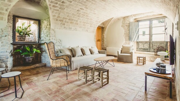 A rustic room with exposed brick walls, a sofa, a wicker chair, a small table, and a television. - Villa Cervia - Six Bedroom Villa, Sleeps 15 (Cervià de Ter)
