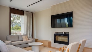 A modern living room with a sofa, chairs, a coffee table, a fireplace, and a TV mounted on the wall. - Villa Lliris - Four Bedroom Villa, Sleeps 10 (Platja d'Aro)