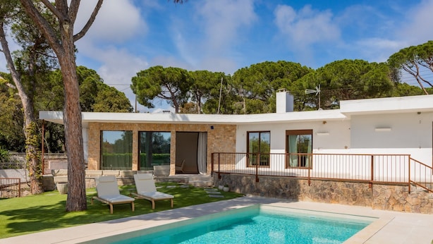 A modern house with a swimming pool, outdoor seating, and a stone wall. - Villa Lliris - Four Bedroom Villa, Sleeps 10 (Platja d'Aro)