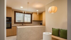 A modern kitchen with built-in appliances, a central island, and a seating area with green cushions. - Villa Lliris - Four Bedroom Villa, Sleeps 10 (Platja d'Aro)
