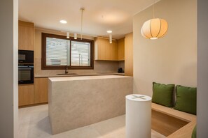 A modern kitchen with built-in appliances, a central island, and a seating area with green cushions. - Villa Lliris - Four Bedroom Villa, Sleeps 10 (Platja d'Aro)