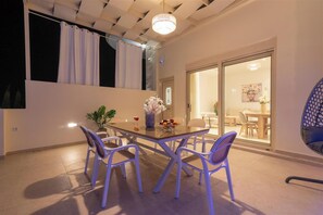A dining area with a table, chairs, and a vase of flowers. - Nerida Luxury Villa 1 (3W3F+8W Ampelouzos)