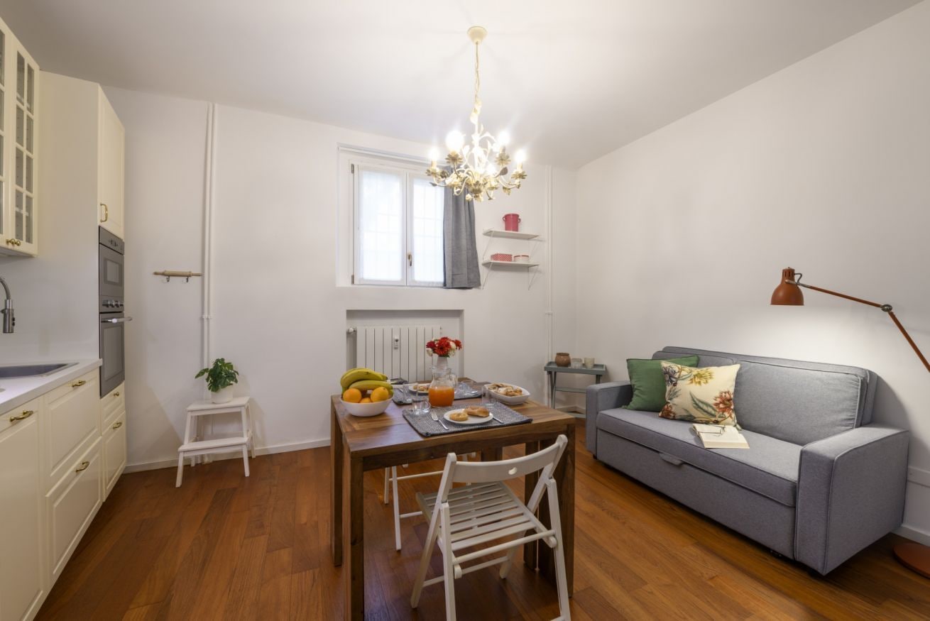 A compact living space with a dining table, a sofa, a kitchenette, and a window.