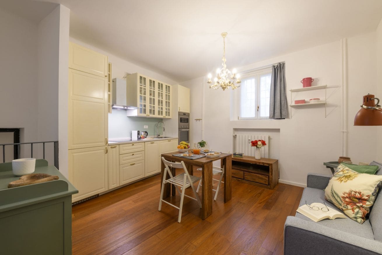 A compact kitchen with a dining table, chairs, and a chandelier.