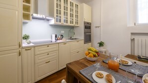 A kitchen with white cabinets, a wooden table, and a fruit bowl. - Marcona, 1 - Quiet two-room Milanese apartment (Milan)