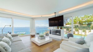 A modern living room with a large TV, comfortable seating, a coffee table, and a view of the ocean. - Luxury Villa Sea Views 6 rooms 12 pax wifi air conditioning (LLucmajor)