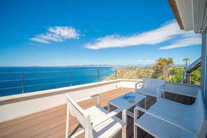 A balcony with white chairs and a table, overlooking a coastal view with the sea and distant land. - Luxury Villa Sea Views 6 rooms 12 pax wifi air conditioning (LLucmajor)