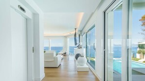 A modern interior with a wooden floor, white furniture, a large window, and a view of the sea. - Luxury Villa Sea Views 6 rooms 12 pax wifi air conditioning (LLucmajor)