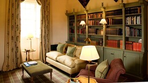 A cozy living room with a sofa, armchair, and a bookshelf filled with books. - Fenton Tower - Six Bedroom Villa, Sleeps 12 (Kingston)