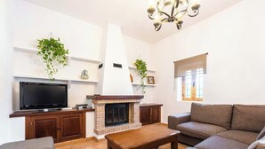 A living room with a fireplace, television, sofa, and a chandelier. - Casa Cala LLonga family house 850 m from the beach (Eivissa)
