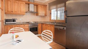A kitchen with wooden cabinets, a stainless steel refrigerator, a microwave, an oven, and a dishwasher. - Casa Cala LLonga family house 850 m from the beach (Eivissa)