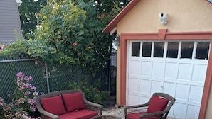 A patio area with wicker furniture, a round table, and a garage door in the background. - 
Welcome to a comfortable, fully furnished 2-bedroom home located mins from  NYC (Bergenfield)