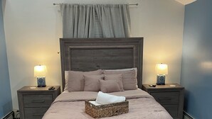 A bedroom with a large bed, two bedside tables with lamps, a headboard, and a window with curtains. - 
Welcome to a comfortable, fully furnished 2-bedroom home located mins from  NYC (Bergenfield)