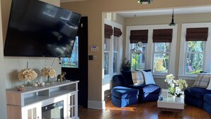 A living room with a flat-screen TV, wooden flooring, a kitchen area, and a seating area with sofas and a coffee table. - 
Welcome to a comfortable, fully furnished 2-bedroom home located mins from  NYC (Bergenfield)