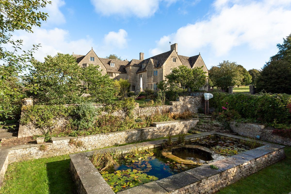 A historic stone building with a pond and surrounding greenery.