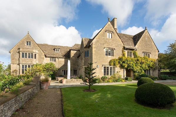 A large stone building with multiple windows and a well-maintained lawn.