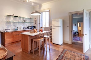 Una cocina moderna con armarios de madera, una vitrina de vidrio, un refrigerador blanco y una zona de comedor con taburetes de bar.