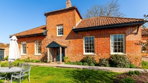 A brick house with a tiled roof, a front door, and a small porch.