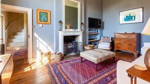 A room with a fireplace, a television, a sofa, a wooden dresser, and a patterned rug.