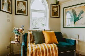 A cozy living room with a green sofa, striped throw, and a vase of flowers.