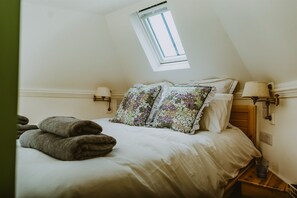 Une chambre à coucher avec un lit, deux lampes fixées au mur, une fenêtre et une petite table de chevet.